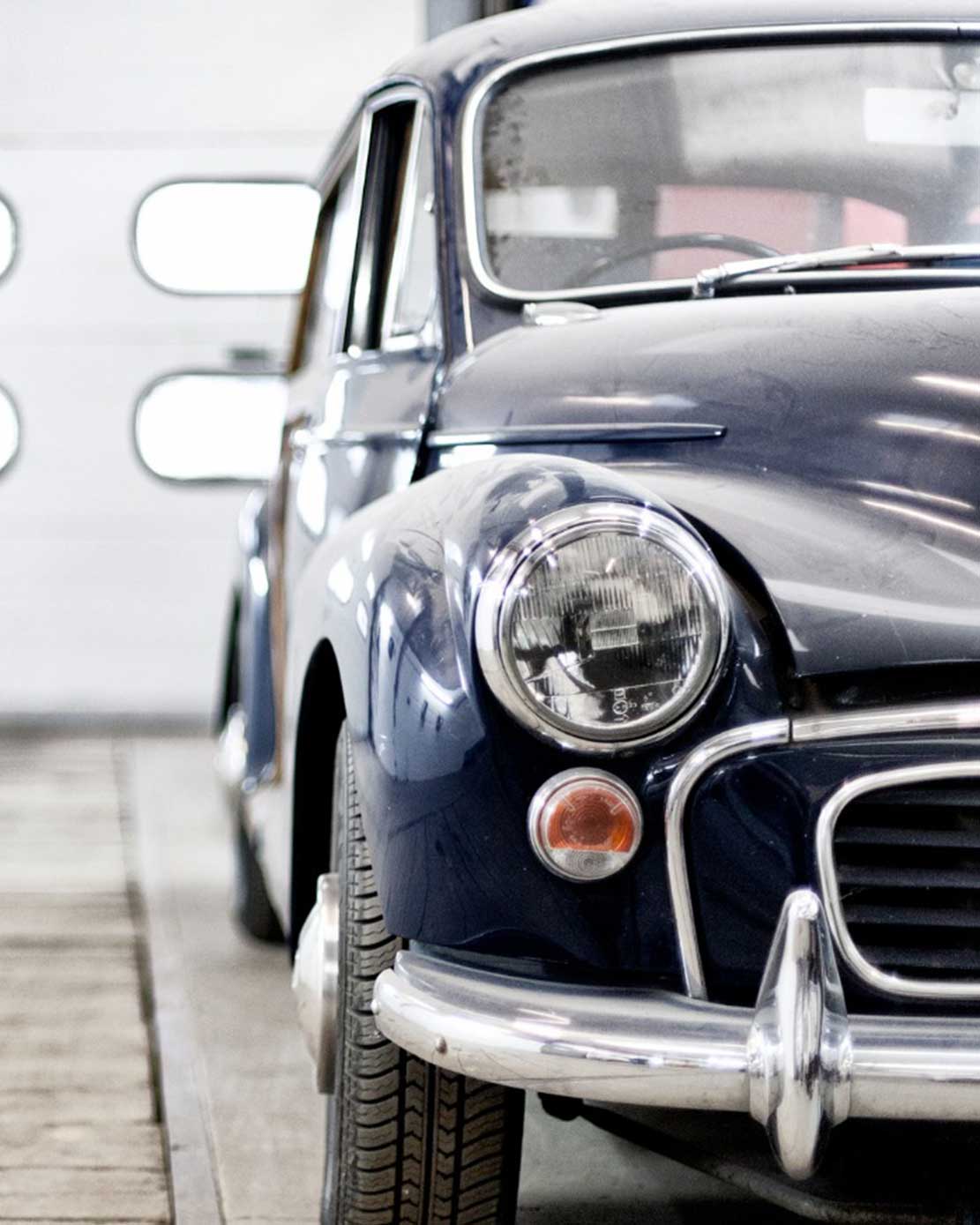 A navy blue vintage car inside a parking garage
