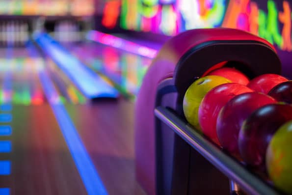 Several colorful balls in the ball collection of a bowling alley