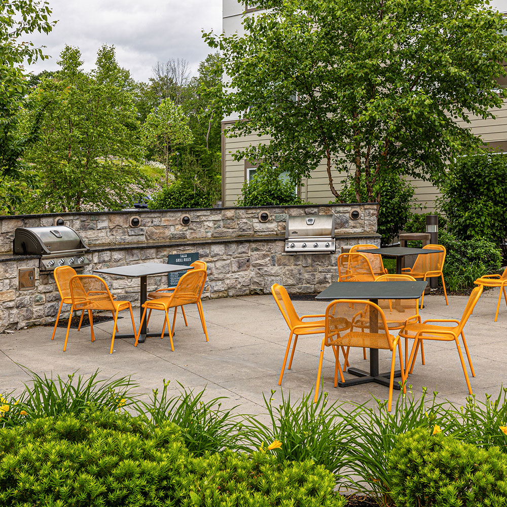 An outdoor deck with two gas grills and tangerine yellow chairs