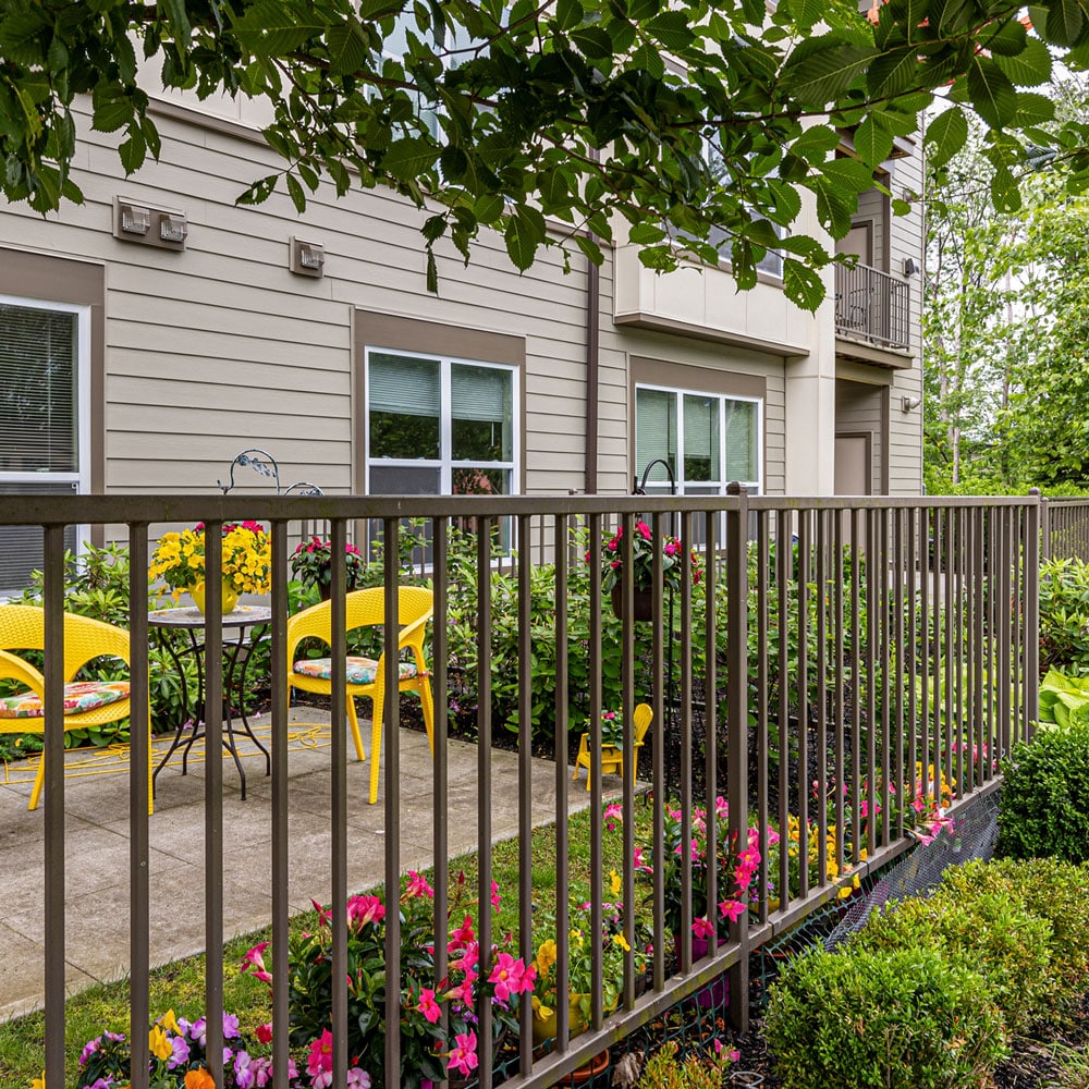 An outdoor apartment patio with a privacy fence and flower bed