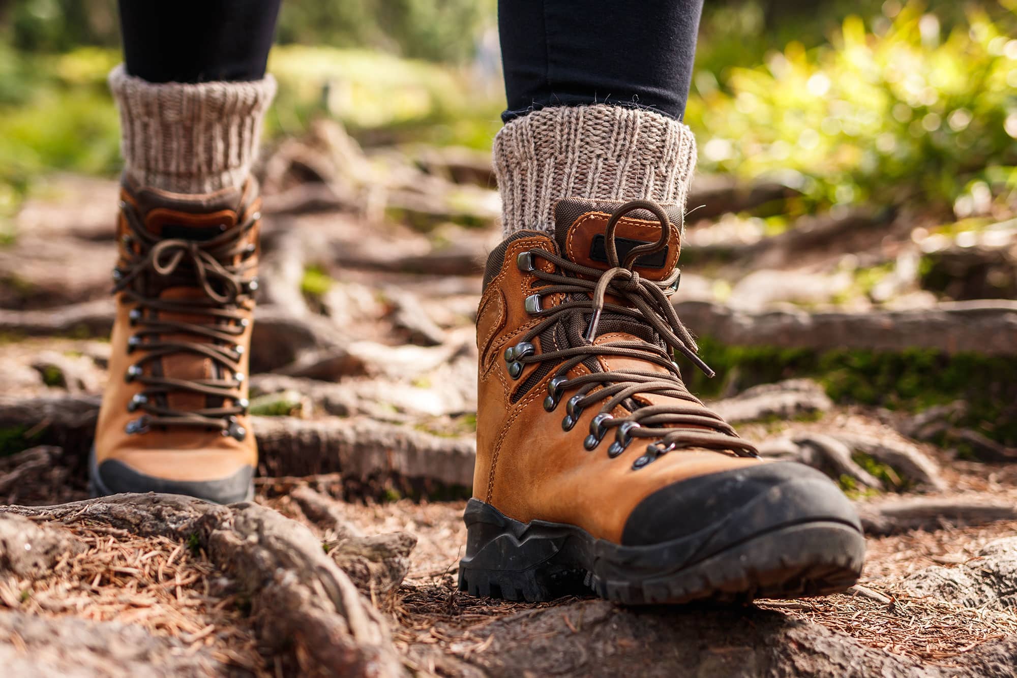A pair of ladies hiking boots trekking through a green forest